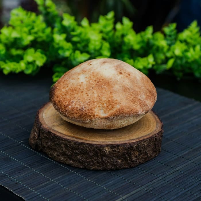 Rundes, frisch gebackenes Fladenbrot auf einem Holzständer